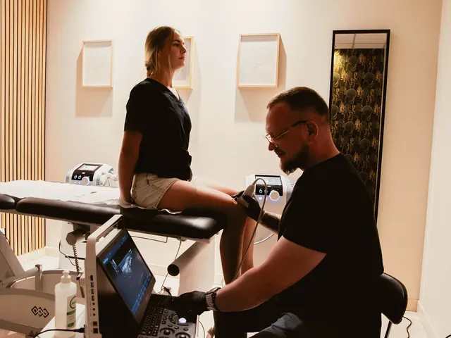 Fizjoterapeuta bada kolano pacjentki głowicą USG i ogląda obraz na ekranie